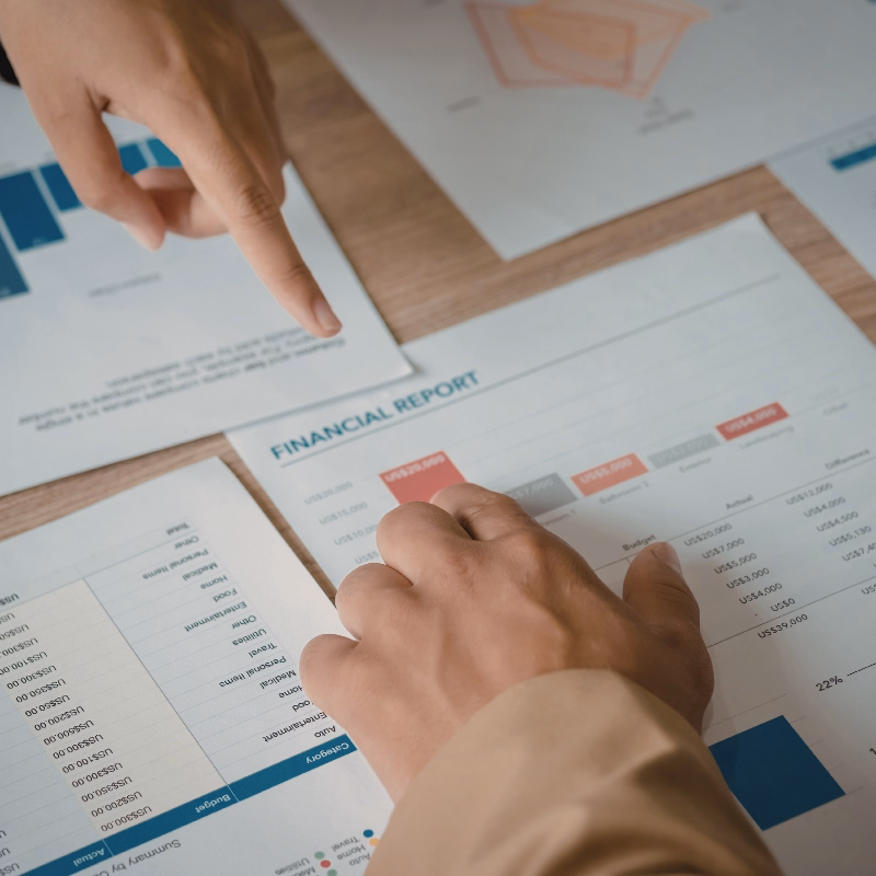 Financial review summary concept image showing a clipboard, pen, glasses, and a laptop with charts on an organized bookkeeping desk