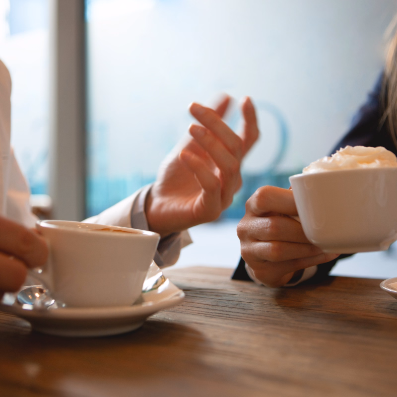 Two professionals seated across from each other in a clean office, having a relaxed conversation