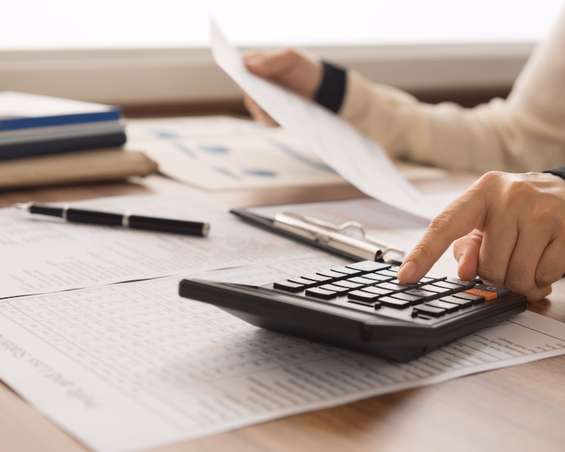 Account organization workspace with grouped folders, chart of accounts planning documents, calculator, and a blurred desktop monitor on a tidy desk