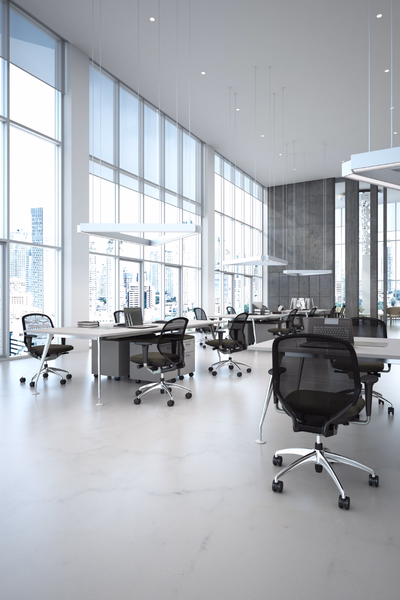 Modern open office with bright natural light, clean workstations, and city views, representing organized monthly bookkeeping and financial reporting services.