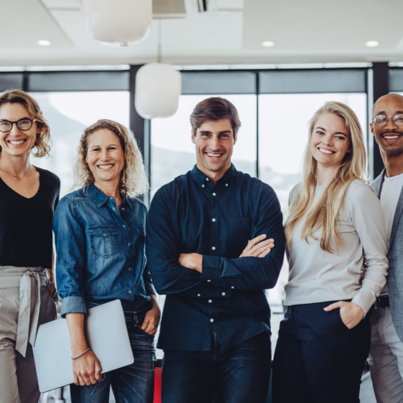 Professional team of five smiling employees standing together in a modern office, representing growing businesses that need reliable monthly bookkeeping and financial reporting