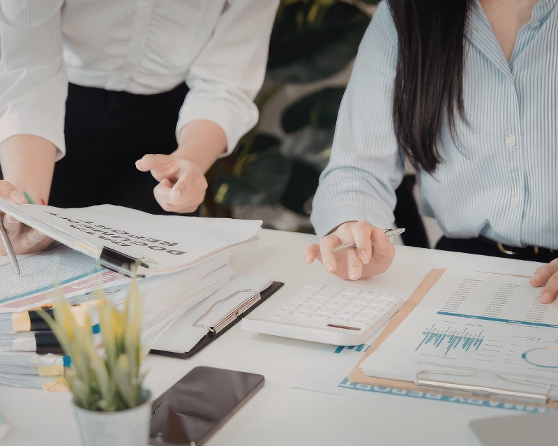 QuickBooks Online assessment concept image showing a desktop monitor, printed reports, calculator, and clipboard during the review stage of cleanup work